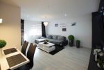 na pierwszym planie fragment jadalni, w oddali salon w luksusowym apartamencie w okolicach Legnicy na sprzedaż