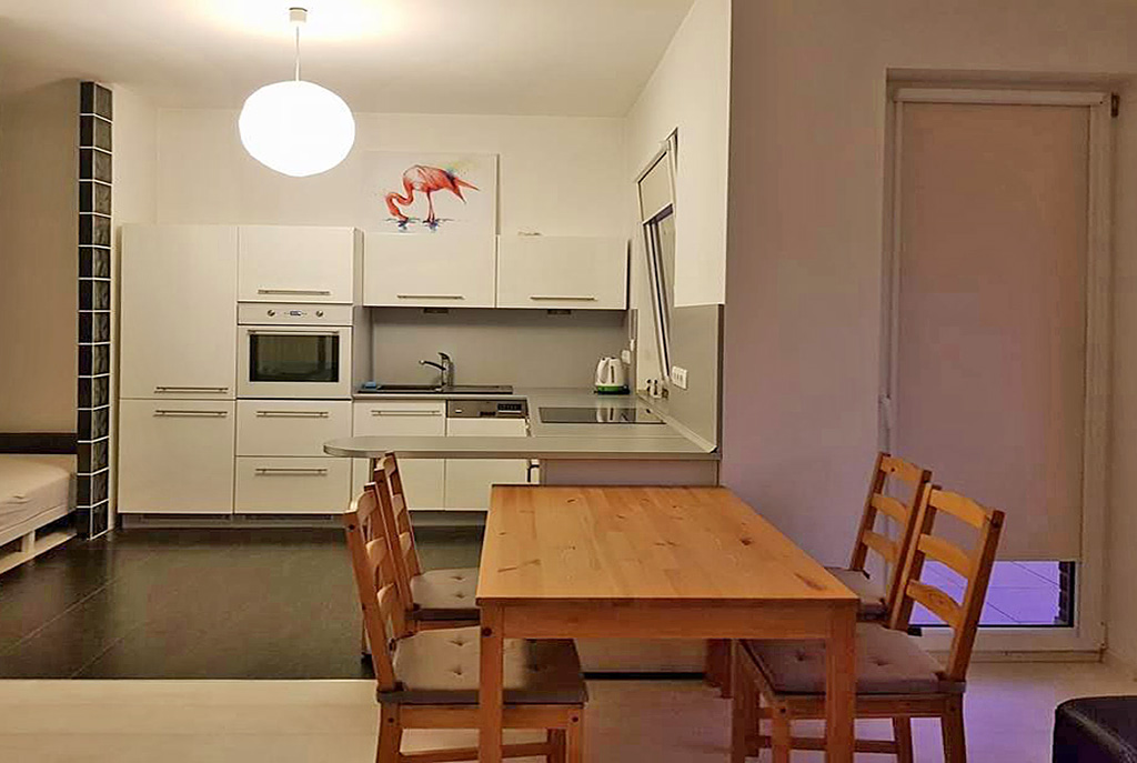 na pierwszym planie jadalnia, w oddali kuchnia w luksusowym apartamencie w Szczecinie na sprzedaż