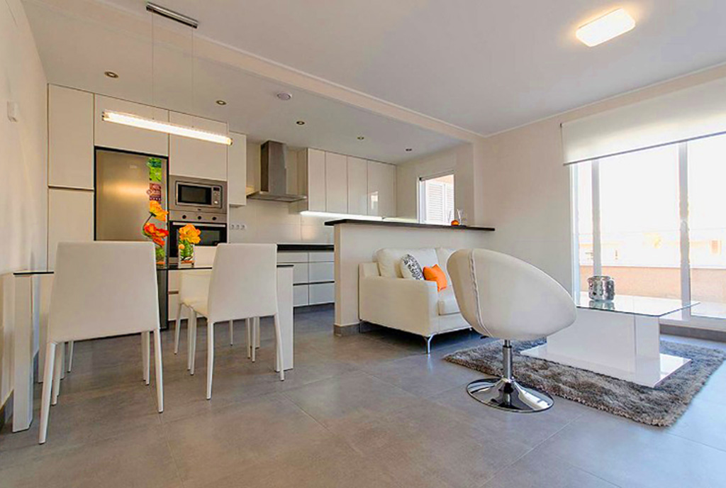 na pierwszym planie salon, w oddali aneks kuchenny w luksusowym apartamencie w Hiszpanii na sprzedaż