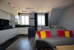 na pierwszym planie salon, w oddali aneks kuchenny w luksusowym apartamencie na Mazurach na sprzedaż