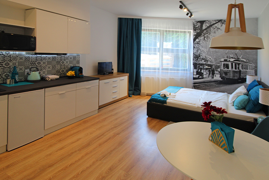 po prawej sypialnia, po lewej aneks kuchenny w luksusowym apartamencie w Krakowie na sprzedaż
