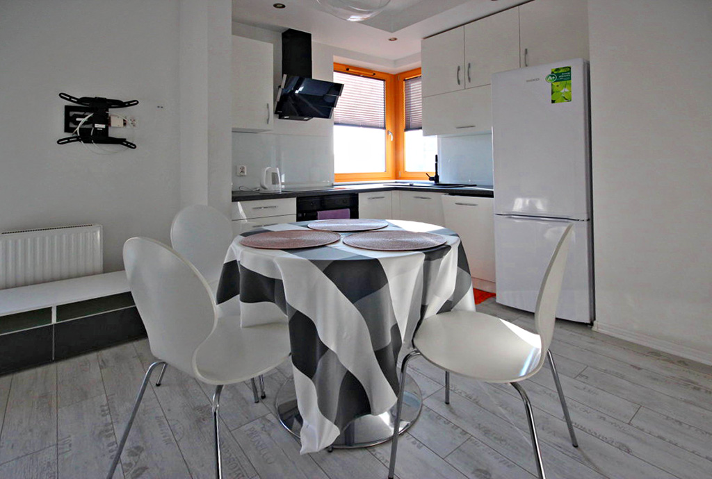 na pierwszym planie jadalnia, w oddali aneks kuchenny w ekskluzywnym apartamencie do wynajmu w Szczecinie