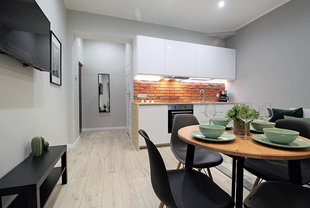 na pierwszym planie jadalnia, w oddali aneks kuchenny w luksusowym apartamencie do sprzedaży Kraków