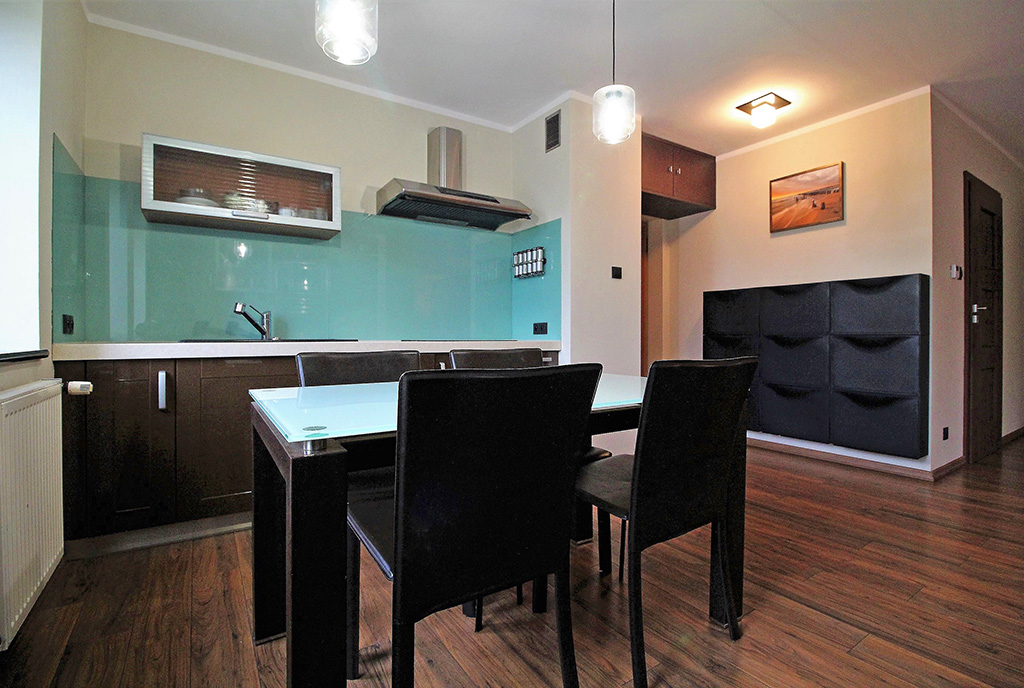na pierwszym planie jadalnia, w oddali kuchnia w ekskluzywnym apartamencie do sprzedaży Kraków