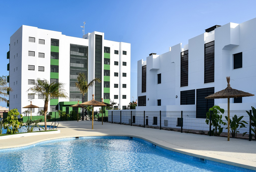 na pierwszym planie basen, w oddali apartamentowiec, gdzie mieści się oferowany na sprzedaż ekskluzywny apartament Mil-Pamlera-Hiszpania