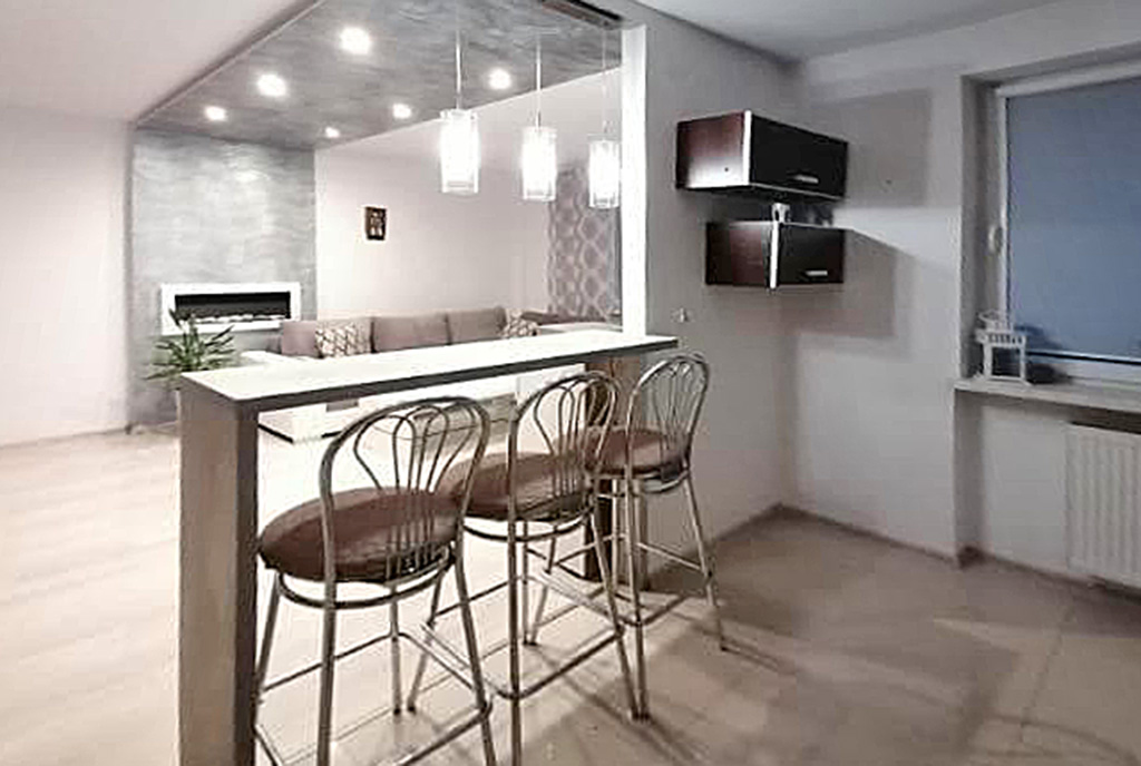 na pierwszym planie jadalnia, w oddali aneks kuchenny w luksusowym apartamencie na sprzedaż Kalisz