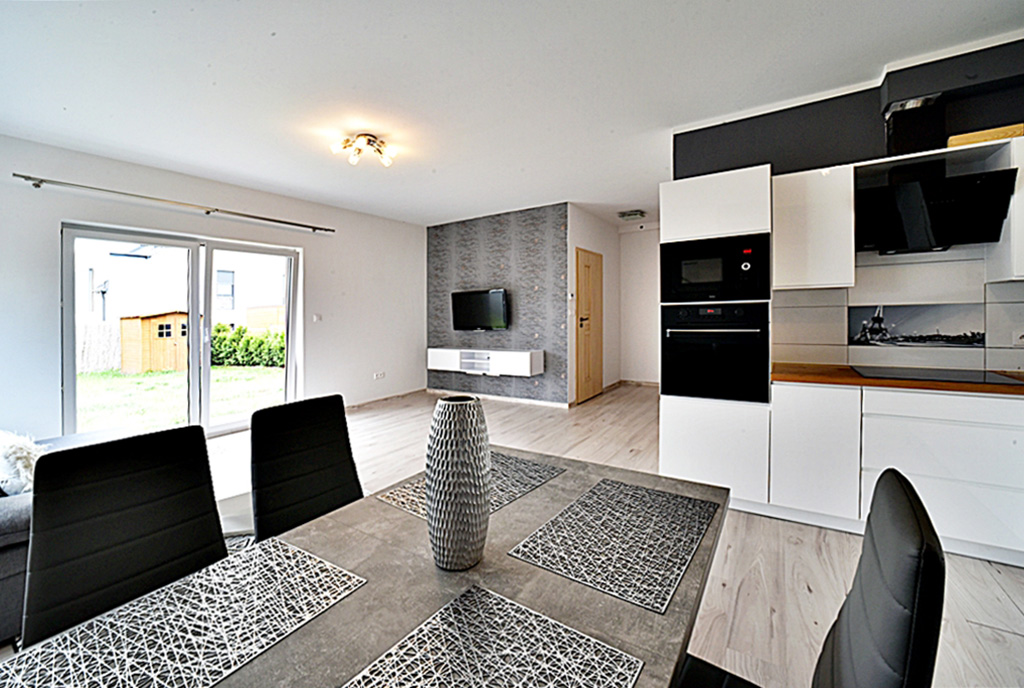 na pierwszym planie jadalnia, w oddali salon w luksusowym apartamencie do wynajmu Bolesławiec