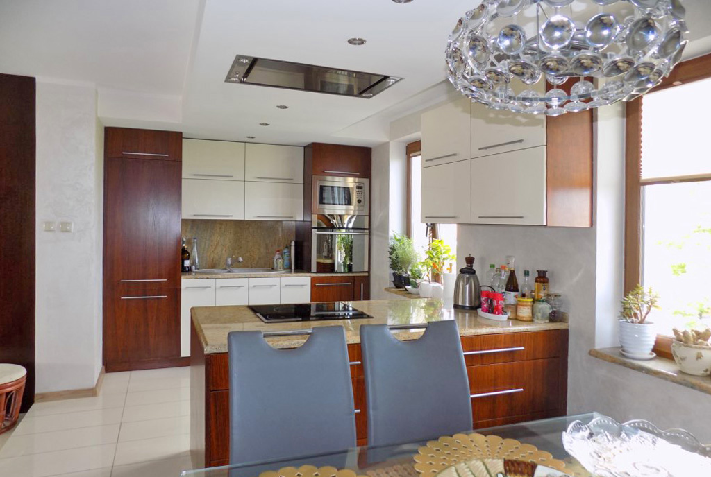 na pierwszym planie jadalnia, w oddali aneks kuchenny w ekskluzywnym apartamencie na sprzedaż Ełk