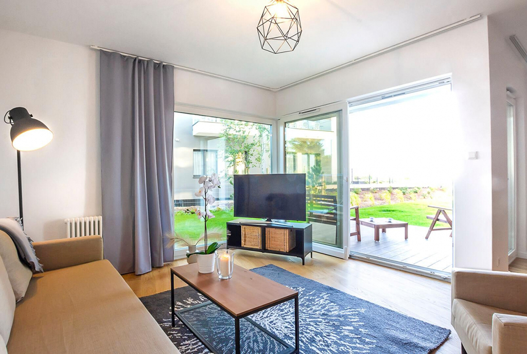 na pierwszym planie salon i wyjście na taras przy luksusowym apartamencie na sprzedaż nad morzem