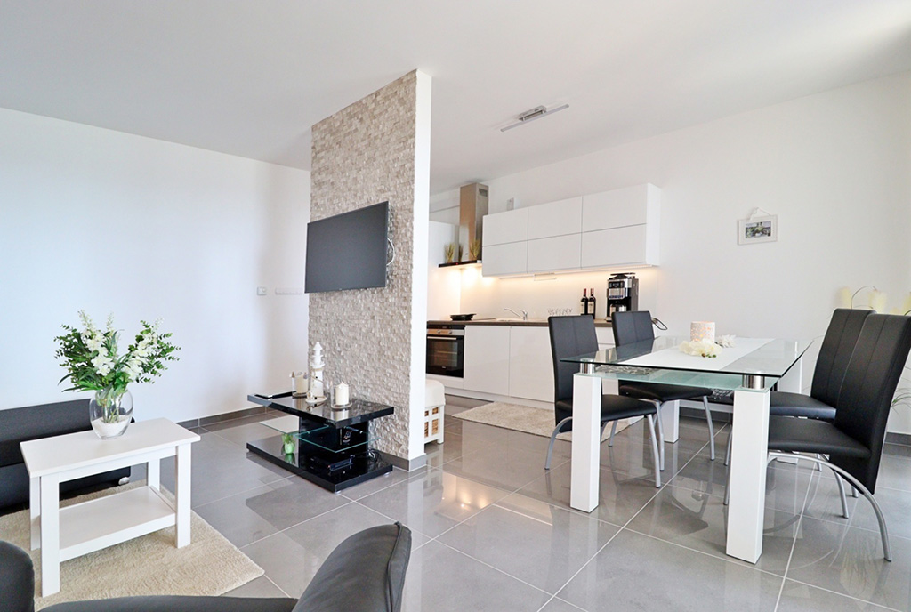 zdjęcie prezentuje pokój dzienny oraz aneks kuchenny w ekskluzywnym apartamencie do sprzedaży nad morzem