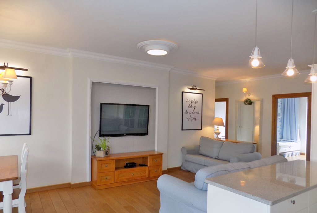 na pierwszym planie pokój dzienny i balkon przy luksusowym apartamencie na sprzedaż Ełk