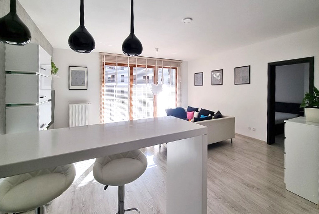 na pierwszym plane aneks kuchenny, w oddali pokój dzienny w luksusowym apartamencie do wynajmu Szczecin
