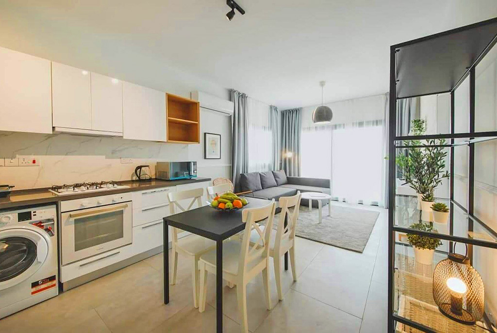 na pierwszym planie jadalnia, w oddali kuchnia w luksusowym apartamencie na sprzedaży Cypr (Iskele)