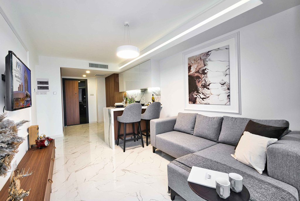 na pierwszym planie salon, w oddali aneks kuchenny i jadalnia w luksusowym apartamencie na sprzedaż Cypr (Iskele)