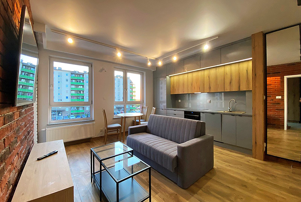 na pierwszym planie salon, w oddali kuchnia w ekskluzywnym apartamencie do wynajmu Wrocław (okolice)