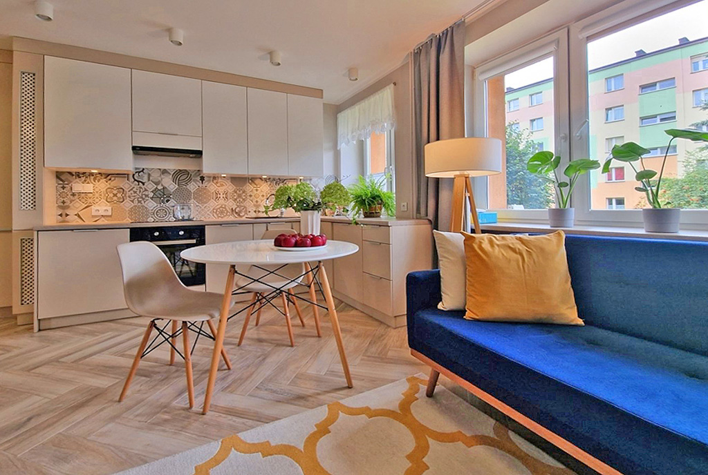 na pierwszym planie salon, potem jadalnia, w oddali aneks kuchenny w ekskluzywnym apartamencie na wynajem Wieluń