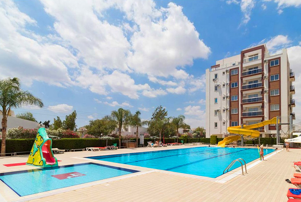 widok od strony basenu na apartamentowiec, w którym znajduje się oferowany na sprzedaż luksusiwy apartament Cypr (Iskele)