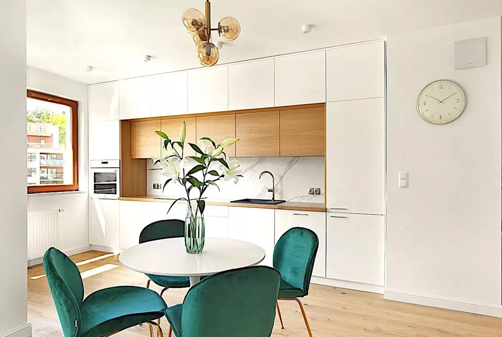 na pierwszym planie jadalnia, w oddali aneks kuchenny w luksusowym apartamencie na sprzedaż Gdynia