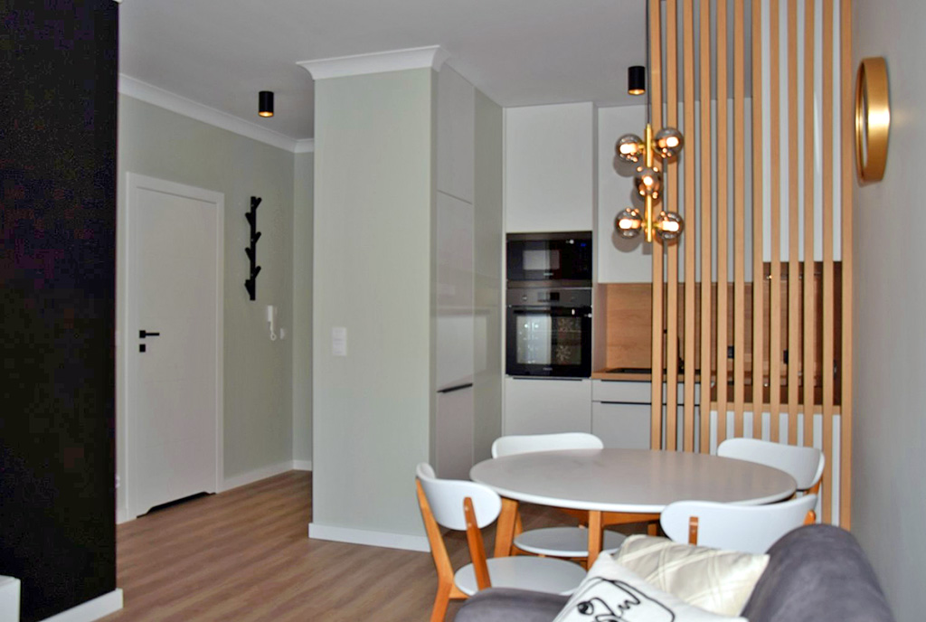 na pierwszym planie jadalnia, w oddali aneks kuchenny w luksusowym apartamencie do wynajmu Słupsk