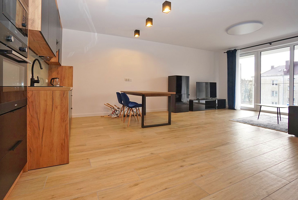 po lewej aneks kuchenny, po prawej salon w ekskluzywnym apartamencie na wynajem Piotrków Trybunalski