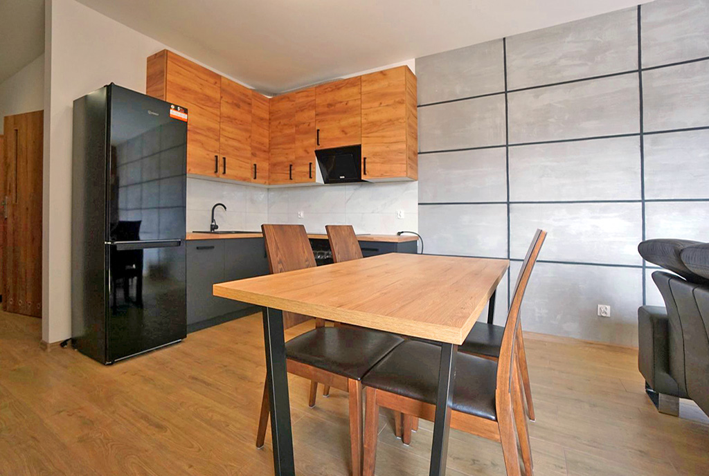 na pierwszym planie jadalnia, w oddali aneks kuchenny w luksusowym apartamencie do wynajmu Piotrków Trybunalski