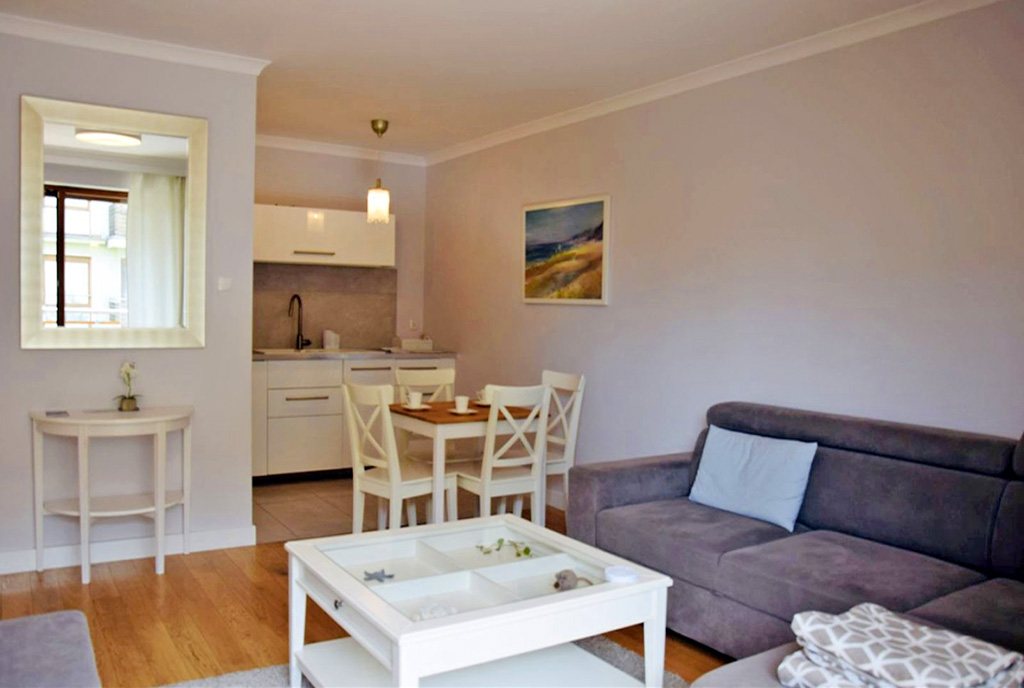 na pierwszym planie pokój dzienny, w oddali aneks kuchenny w ekskluzywnym apartamencie na wynajem Ustka