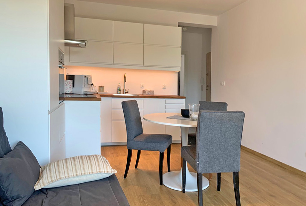 na pierwszym planie jadalnia, w oddali aneks kuchenny w luksusowym apartamencie na wynajem Wrocław