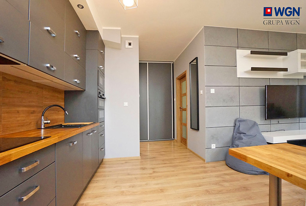 po lewej kuchnia, po prawej salon w luksusowym apartamencie do wynajmu Konin