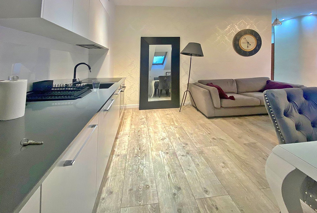 po lewej kuchnia, po prawej salon w ekskluzywnym apartamencie na wynajem Szczecin