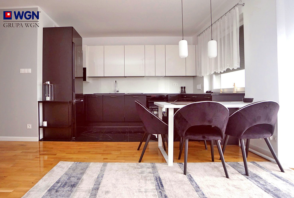 na pierwszym planie jadalnia, w oddali kuchnia w ekskluzywnym apartamencie na sprzedaż Konin