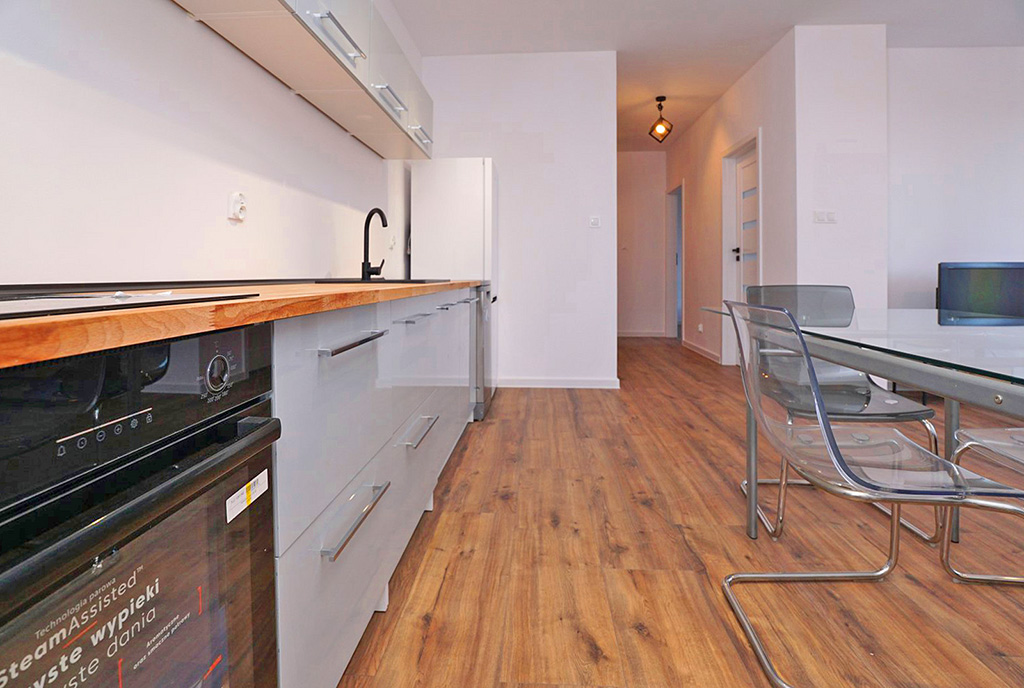 po lewej kuchnia, po prawej salon w luksusowym apartamencie na sprzedaż Piotrków Trybunalski