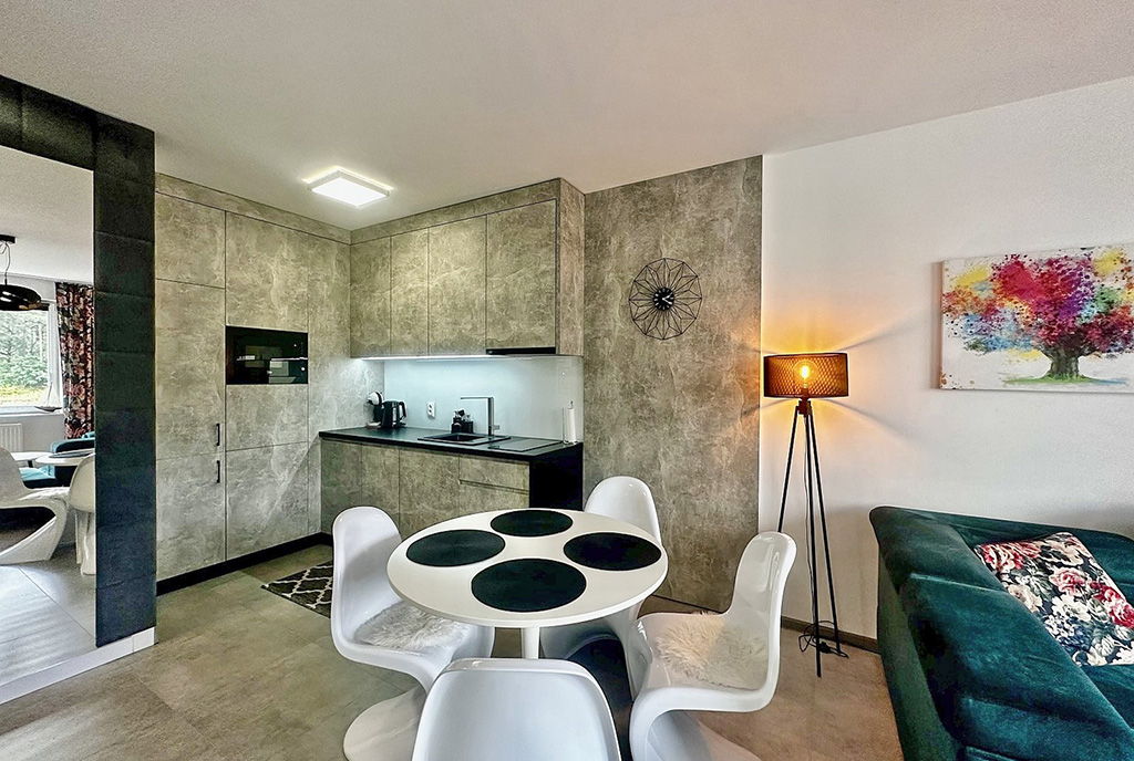 na pierwszym planie jadalnia, w oddali kuchnia w luksusowym apartamencie na sprzedaż nad morzem