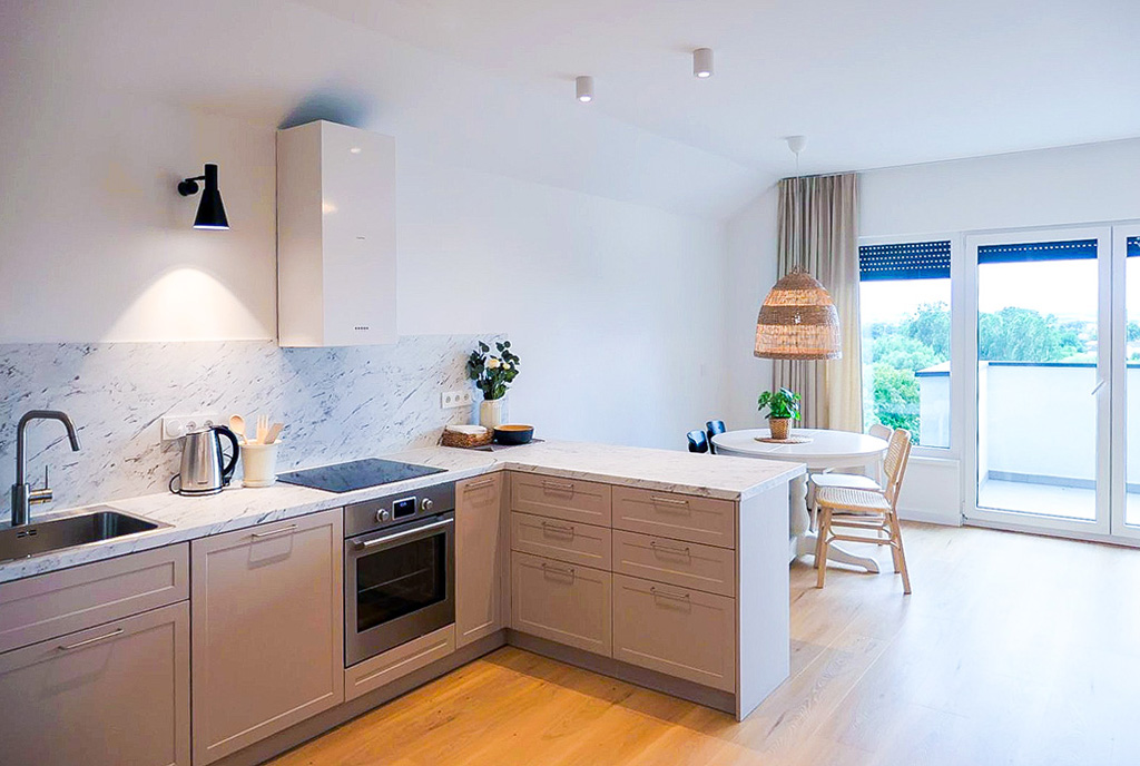 na pierwszym planie kuchnia, w oddali salon w luksusowym apartamencie do wynajmu Kwidzyn