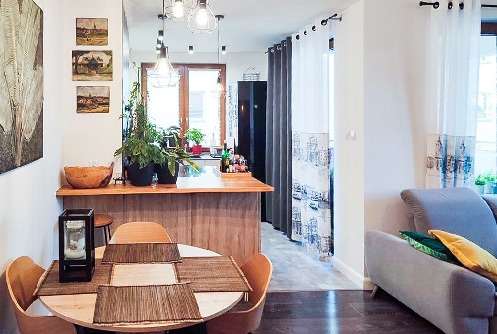 na pierwszym planie jadalnia, w oddali kuchnia w luksusowym apartamencie na sprzedaż Ełk