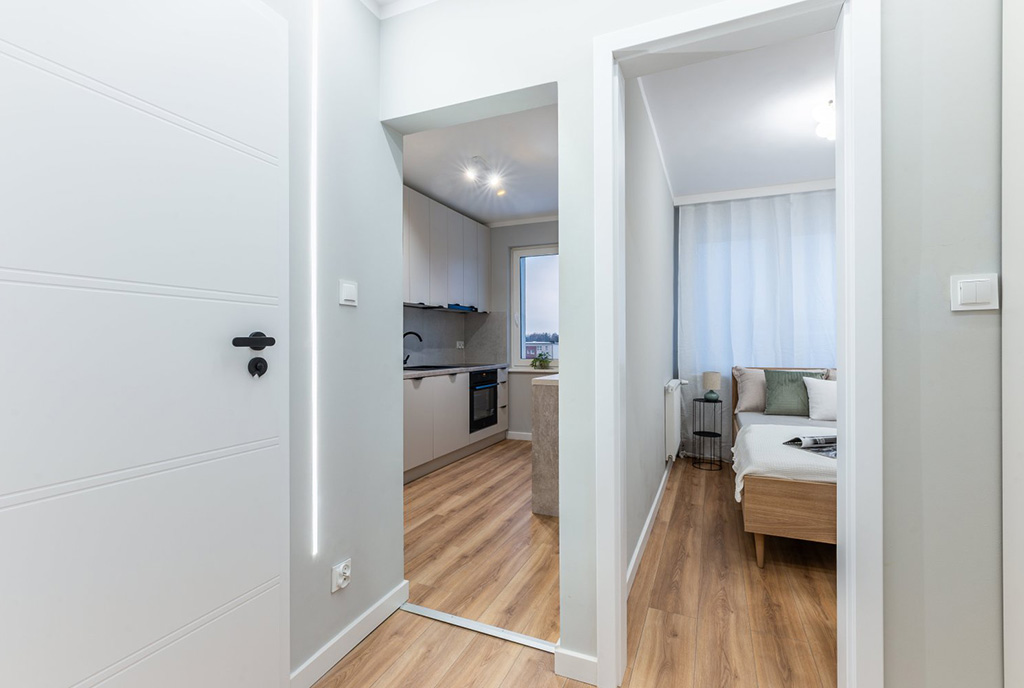 po lewej kuchnia, po prawej sypialnia w ekskluzywnym apartamencie na sprzedaż Gdynia okolice