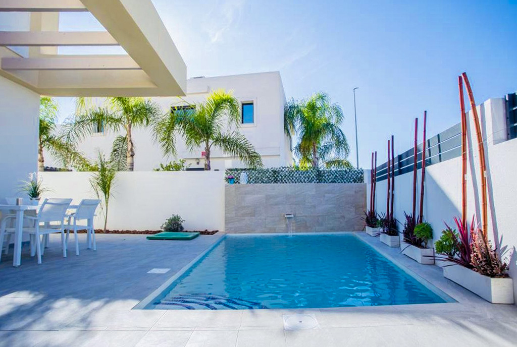 na pierwszym planie basen, w oddali ekskluzywna willa do sprzedaży Hiszpania Los Montesinos