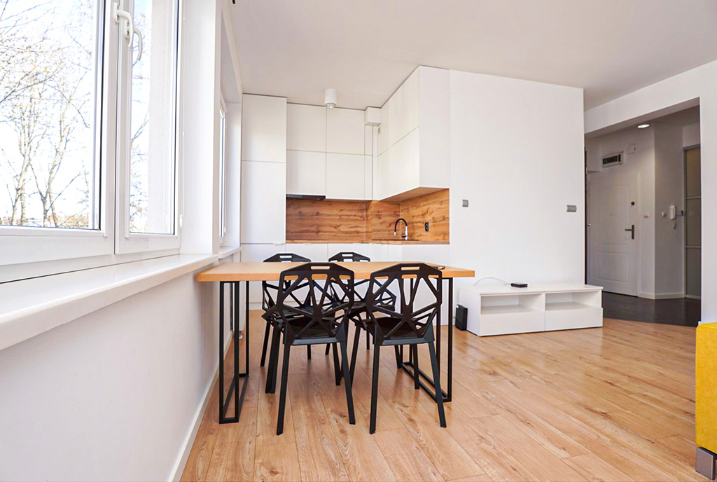 na pierwszym plani jadalnia, w oddali kuchnia w luksusowym apartamencie na sprzedaż Piotrków Trybunalski