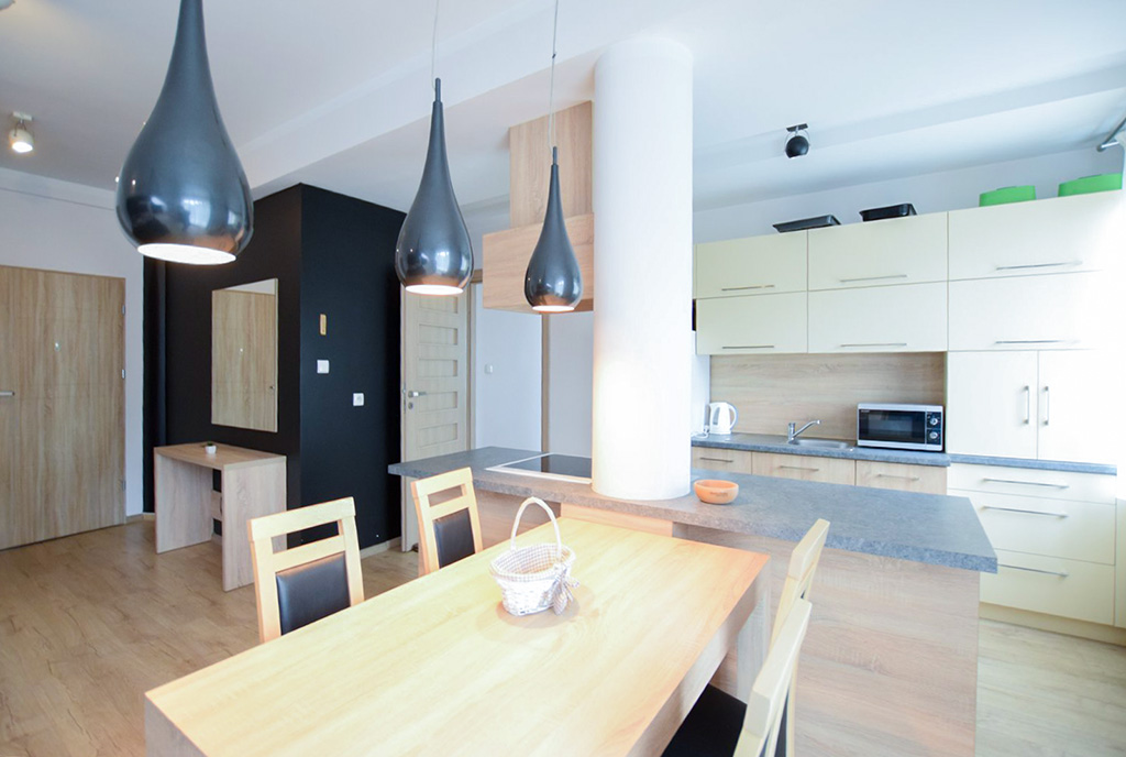 zdjęcie prezentuje komfortową jadalnię oraz aneks kuchenny w ekskluzywnym apartamencie na wynajem Suwałki