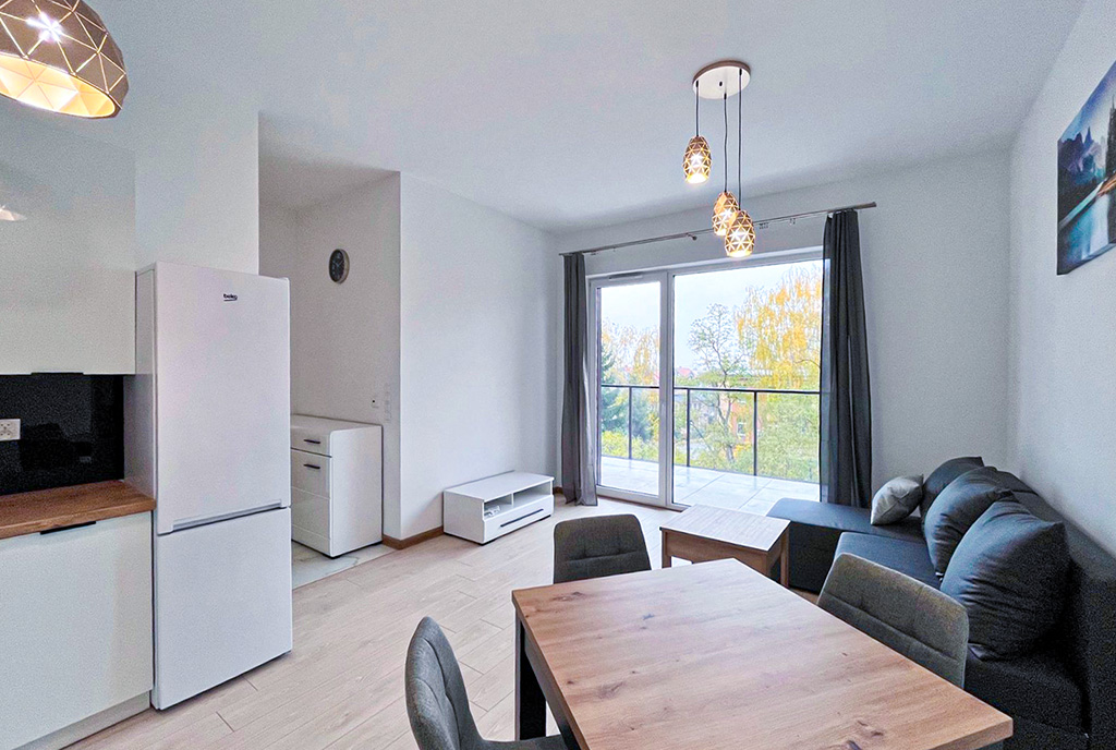 na pierwszym planie jadalnia i salon w luksusowym apartamencie do wynajmu Mazury