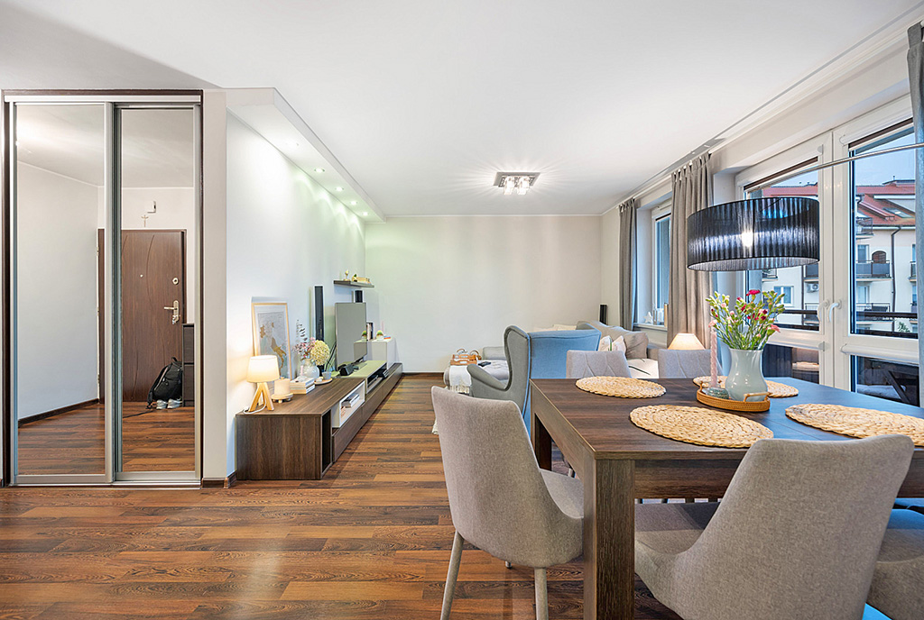 na pierwszym planie jadalnia, w oddali salon w luksusowym apartamencie na sprzedaż Grudziądz