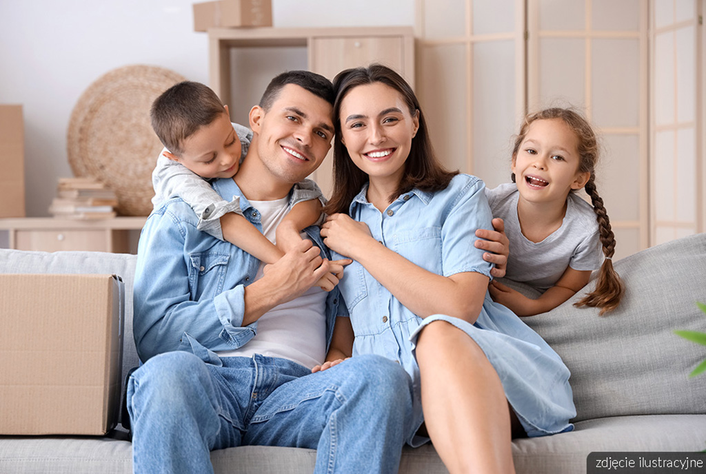 na zdjęciu uśmiechnięta rodzina pozująca w pokoju dziennym ekskluzywnego apartamentu na sprzedaż Gdańsk