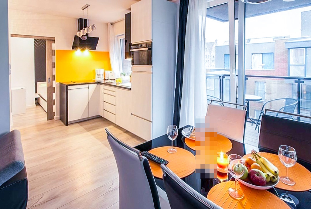 na pierwszym planie jadalnia, w oddali kuchnia w luksusowym apartamencie na sprzedaż Gdańsk