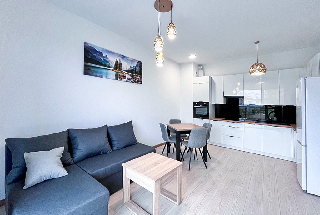 po lewej salon, po prawej kuchnia w luksusowym apartamencie do wynajmu Mazury