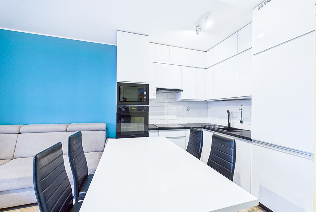 na pierwszym planie jadalnia, w oddali kuchnia w luksusowym apartamencie na sprzedaż Poznań (okolice)