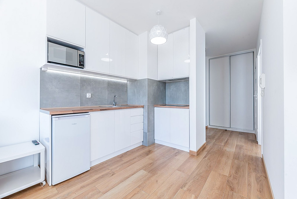 zaaranżowana w bieli kuchnia w luksusowym apartamencie na sprzedaż nad morzem