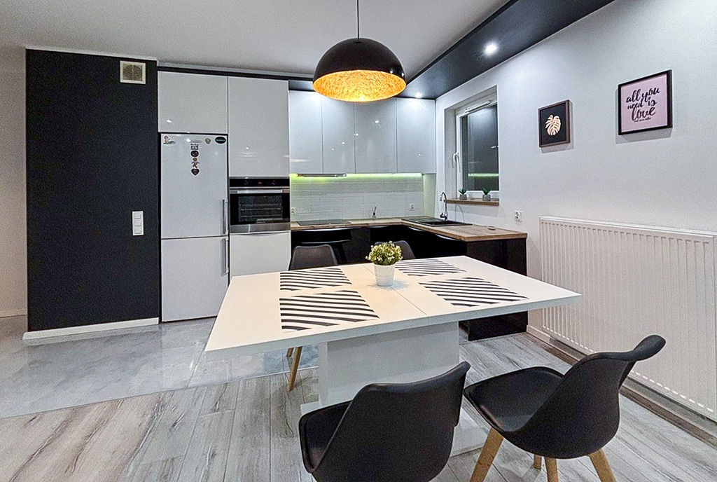 na pierwszym planie jadalnia, w oddali aneks kuchenny w luksusowym apartamencie na sprzedaż Szczecin