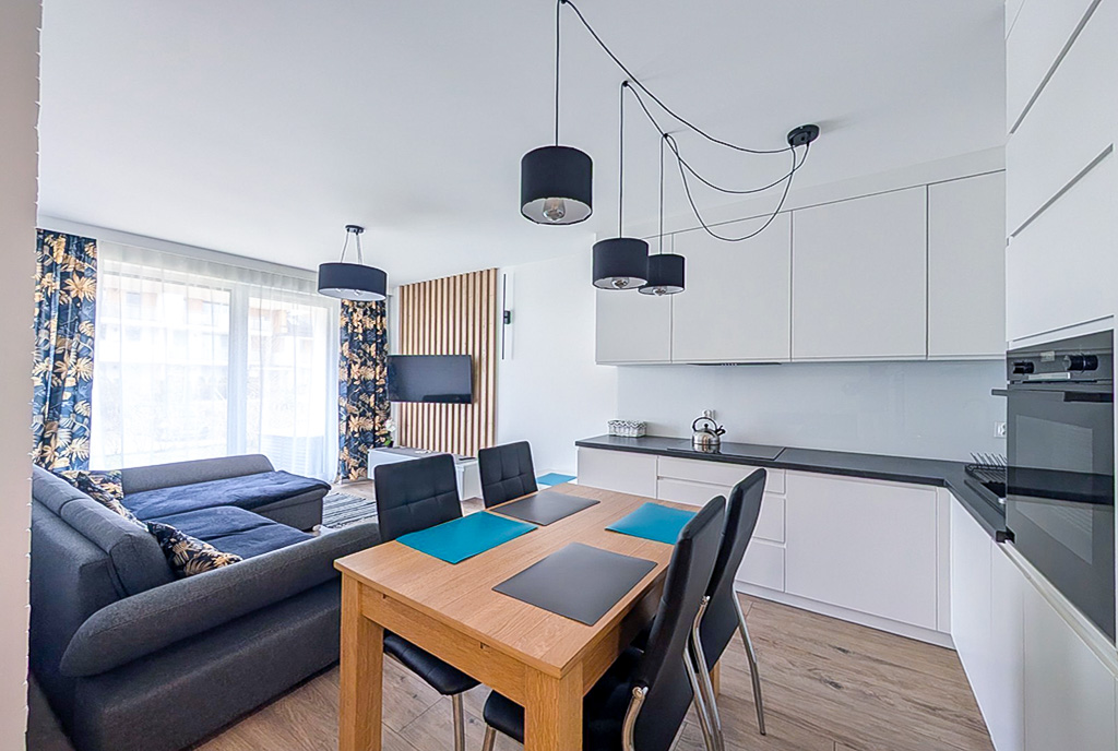 na pierwszym planie jadalnia, w oddali kuchnia w luksusowym apartamencie na sprzedaż Gdańsk (okolice)